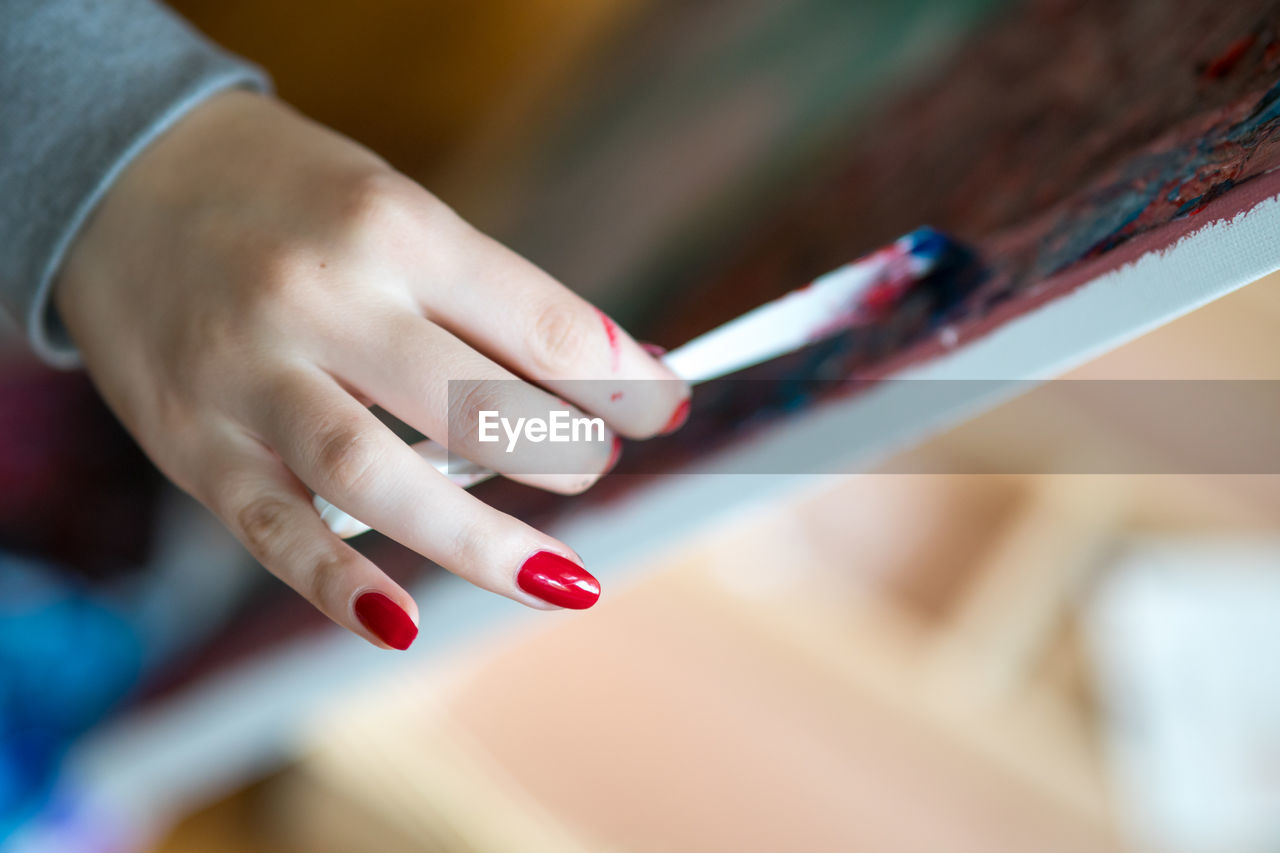 Female artist's hand holding brush and painting