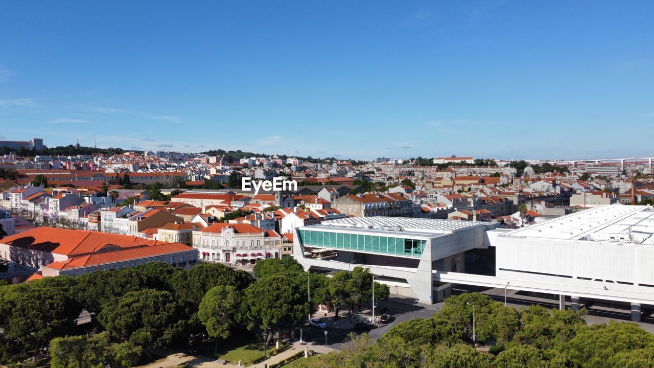 HIGH ANGLE VIEW OF BUILDINGS IN CITY AGAINST BLUE SKY