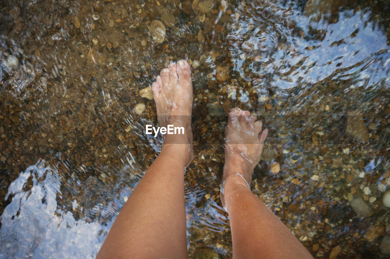 LOW SECTION OF PERSON FEET IN WATER