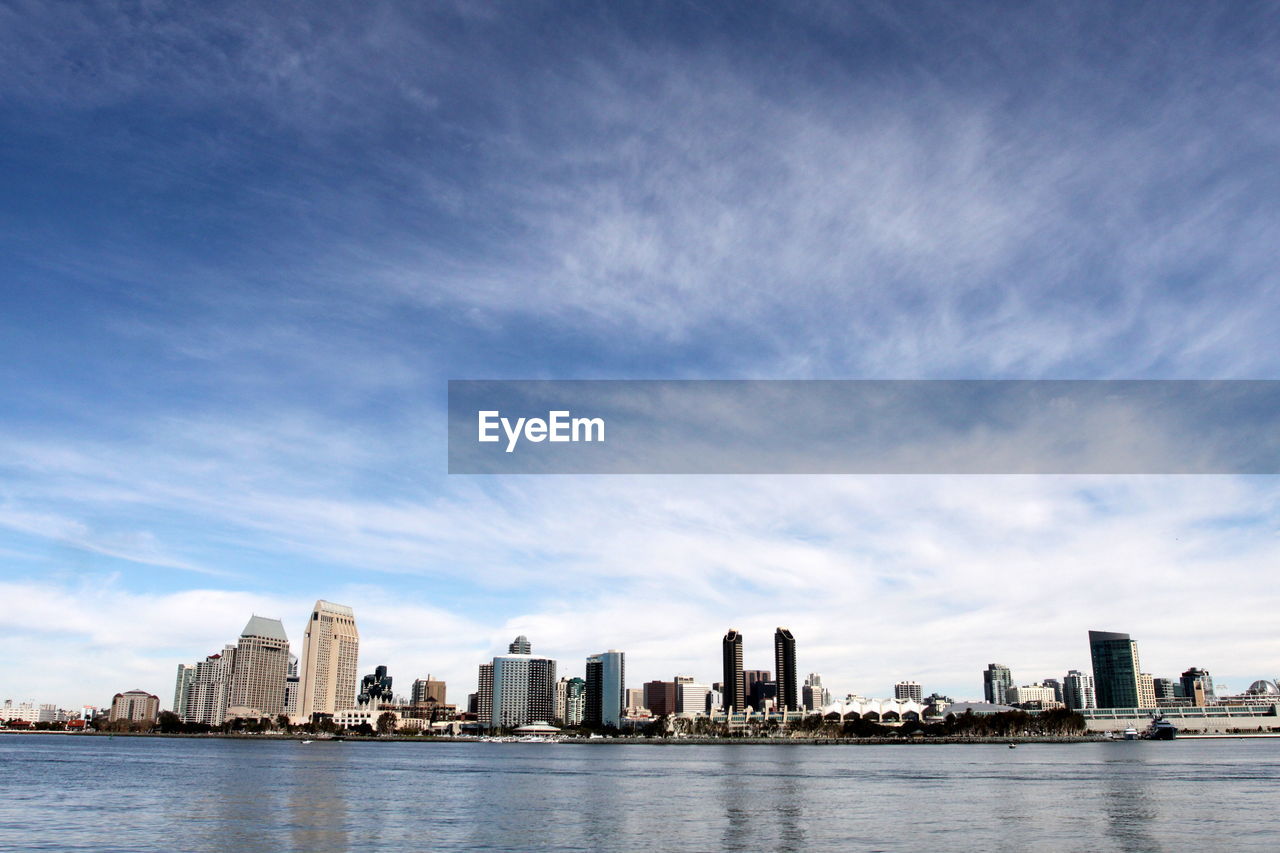 City at waterfront against cloudy sky