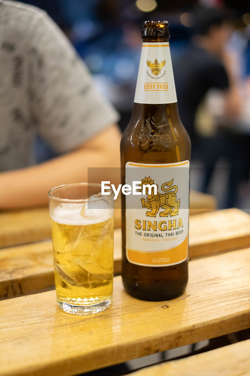 CLOSE-UP OF BEER IN GLASS ON TABLE AGAINST WOODEN BACKGROUND