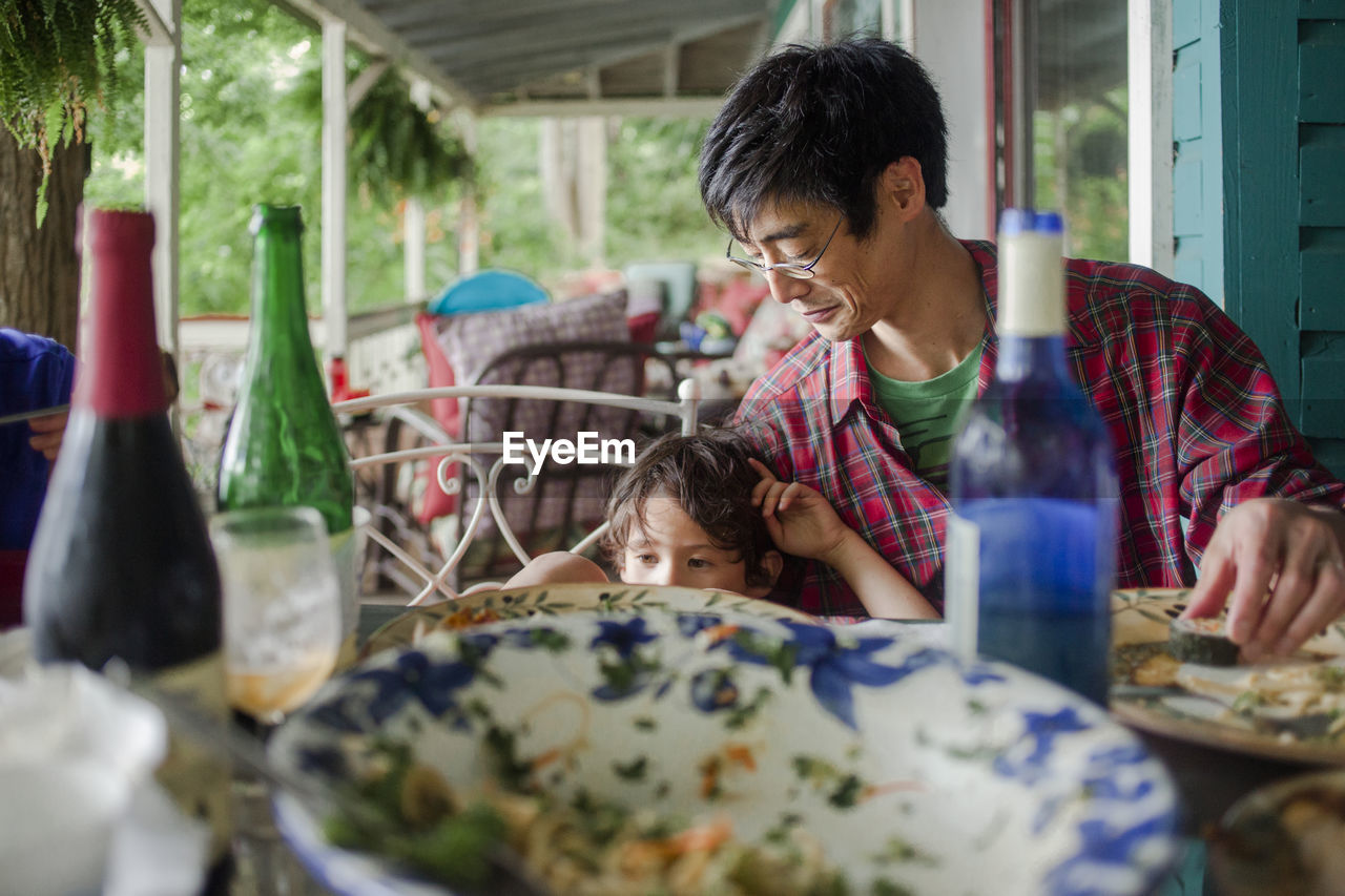 Father and son having lunch at dining table on porch