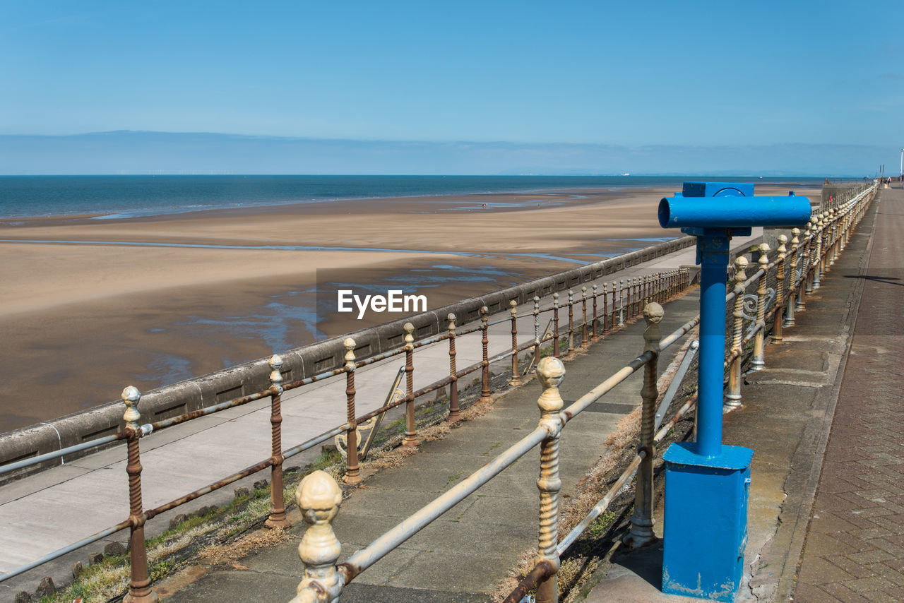 Blue binoculars at beach against sky