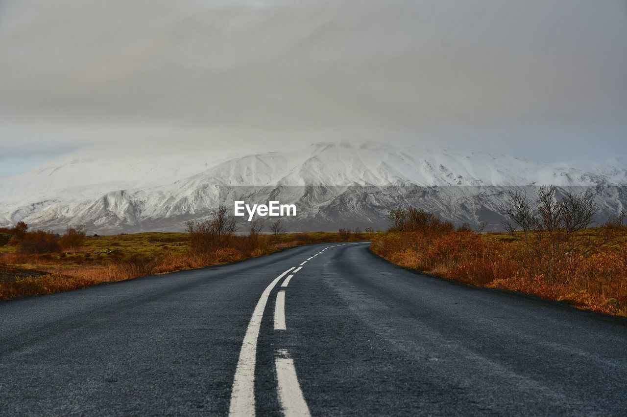 Empty road leading towards snowcapped mountain