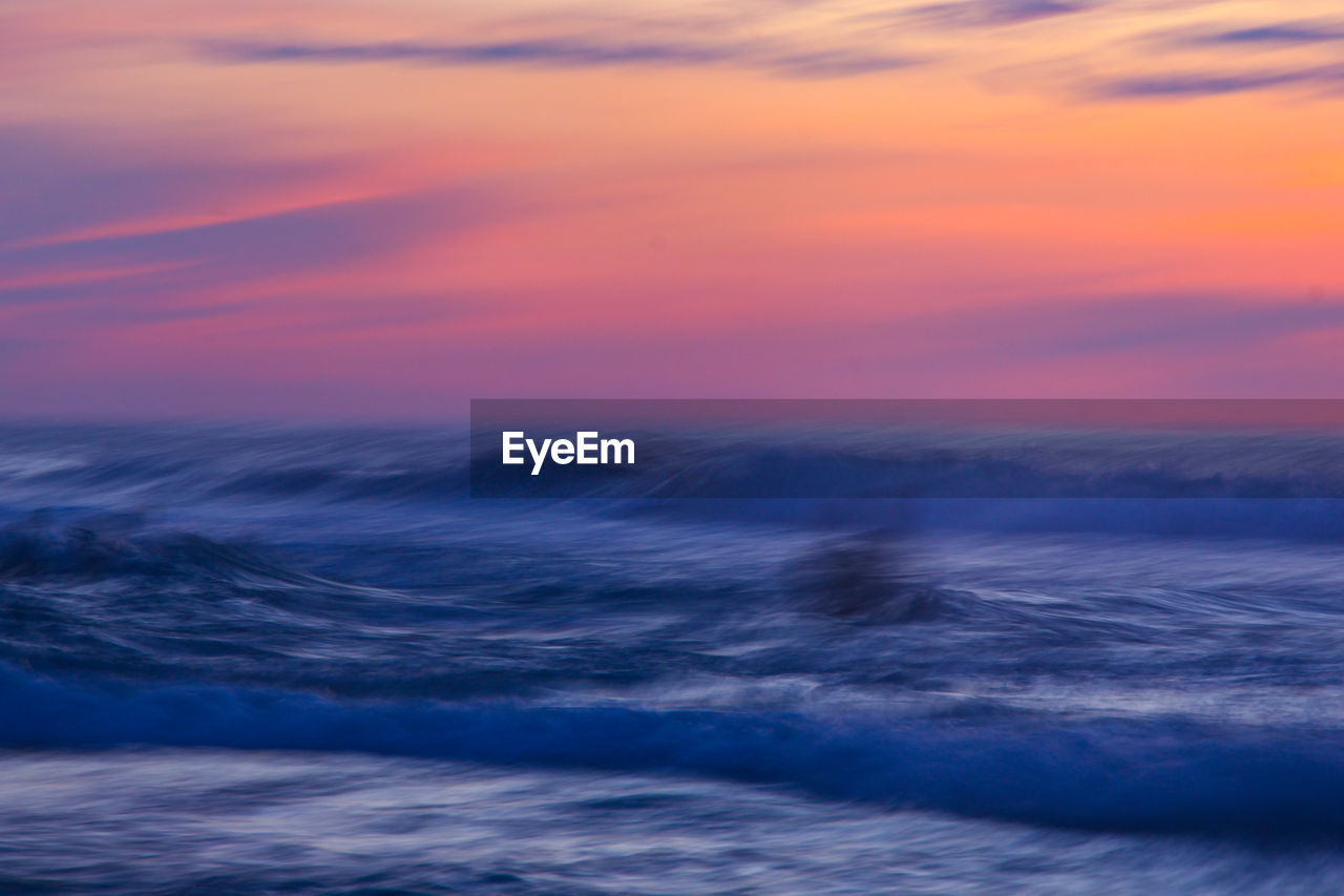 Scenic view of sea against dramatic sky during sunset