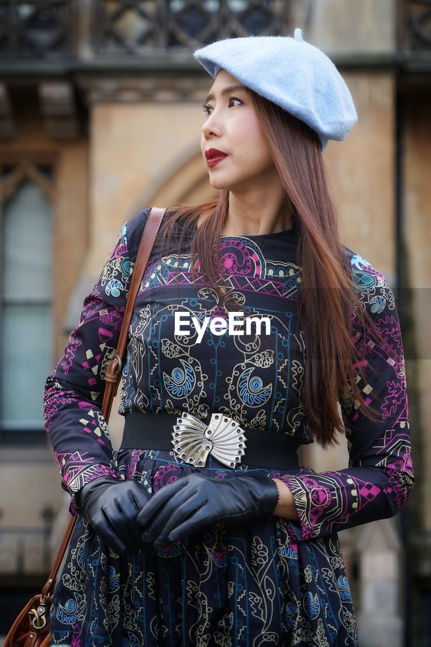 Woman looking away while standing in city