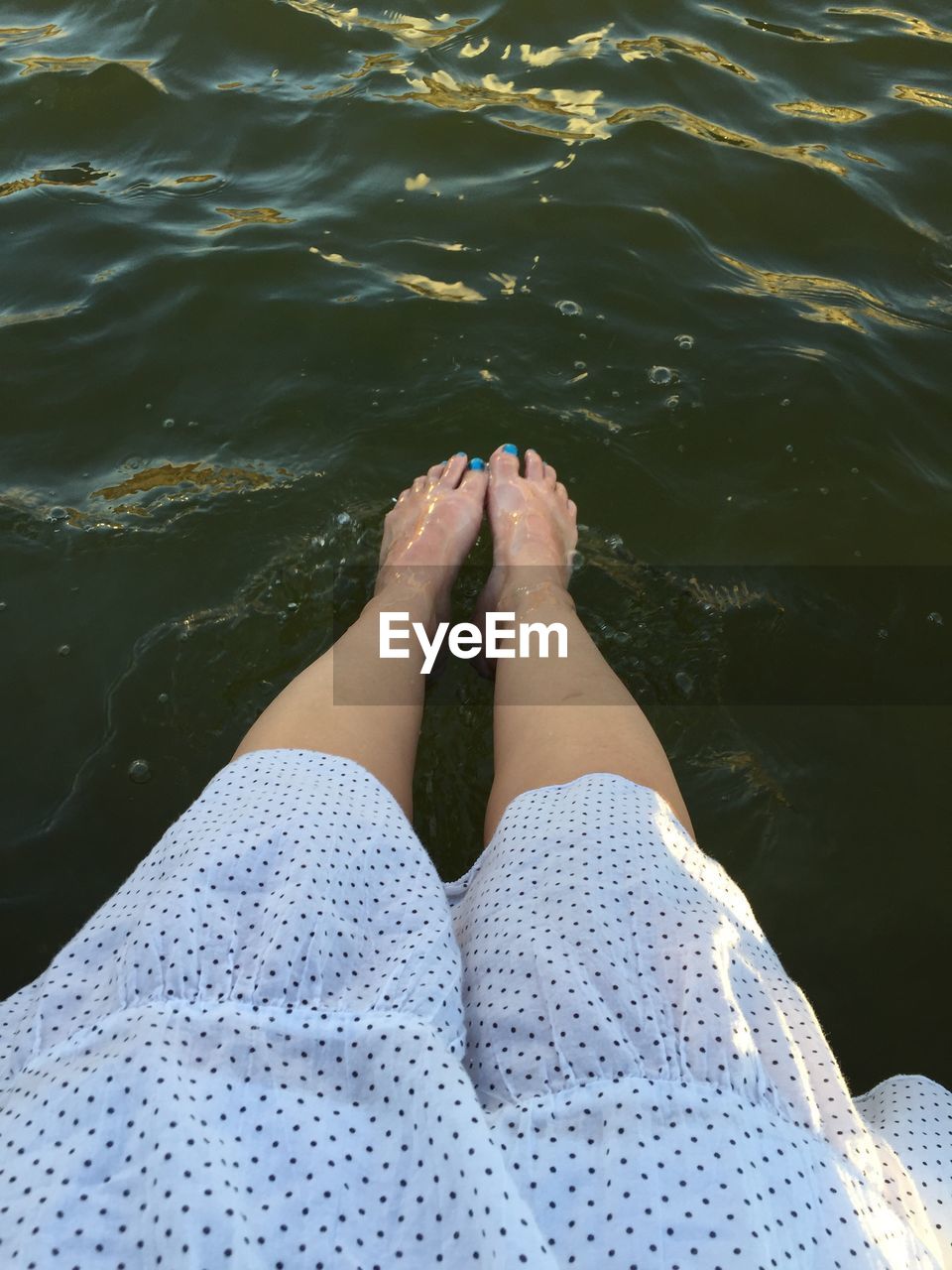 Low section of woman with legs in lake