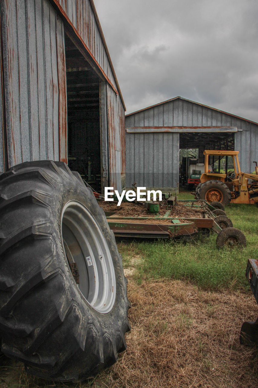 transportation, wheel, tire, field, day, abandoned, no people, cloud - sky, architecture, outdoors, sky, stationary, built structure, grass