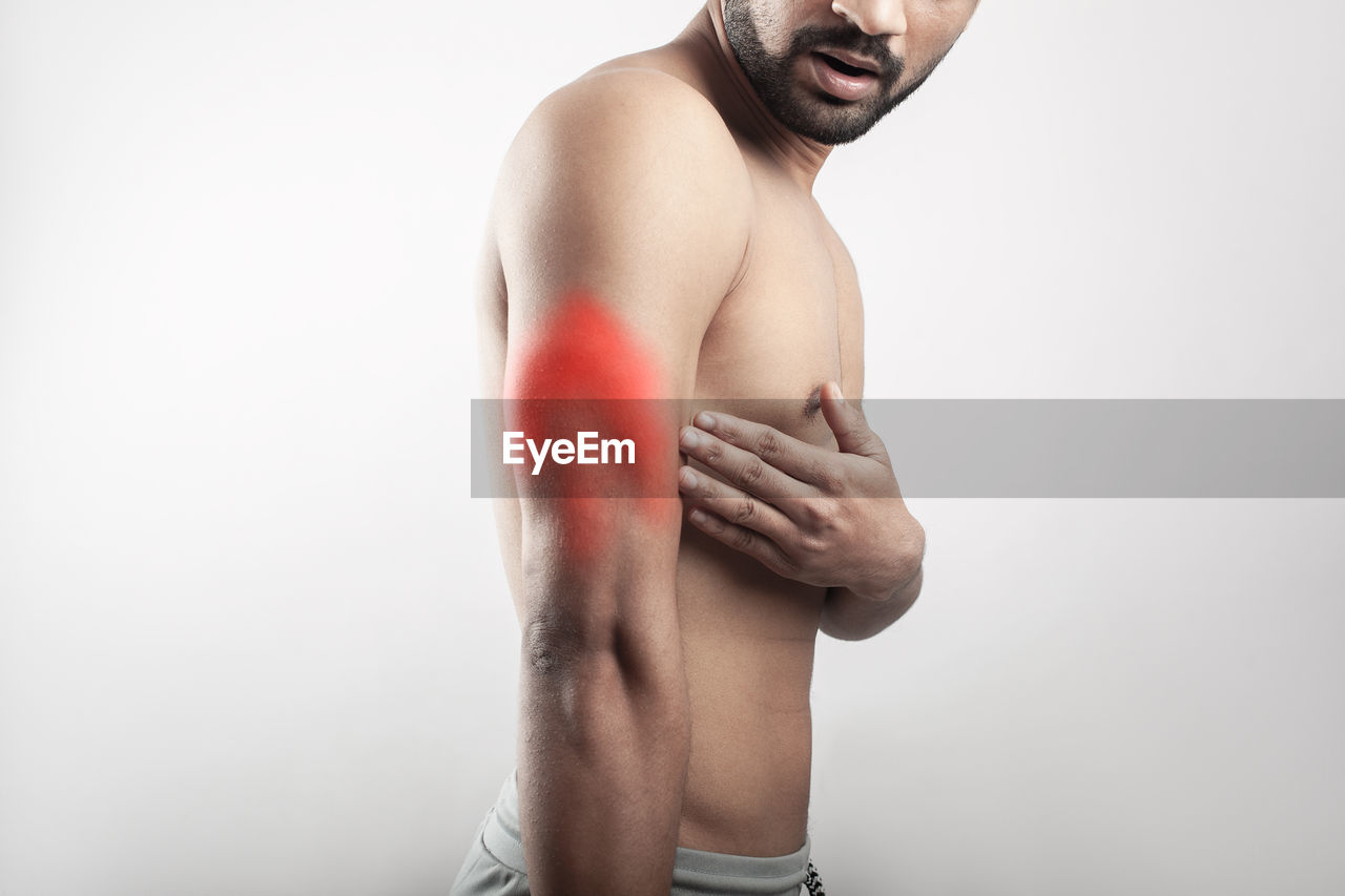 adult, studio shot, arm, one person, muscular build, men, indoors, strength, limb, athlete, lifestyles, young adult, exercising, portrait, wellbeing, human muscle, sports training, waist up, sports, undergarment, vitality, standing, gray background, healthcare and medicine, white background, clothing, masculinity, beard, copy space, finger, gray, briefs, player, facial hair, emotion, hand, human face, photo shoot, pain, trunk, person