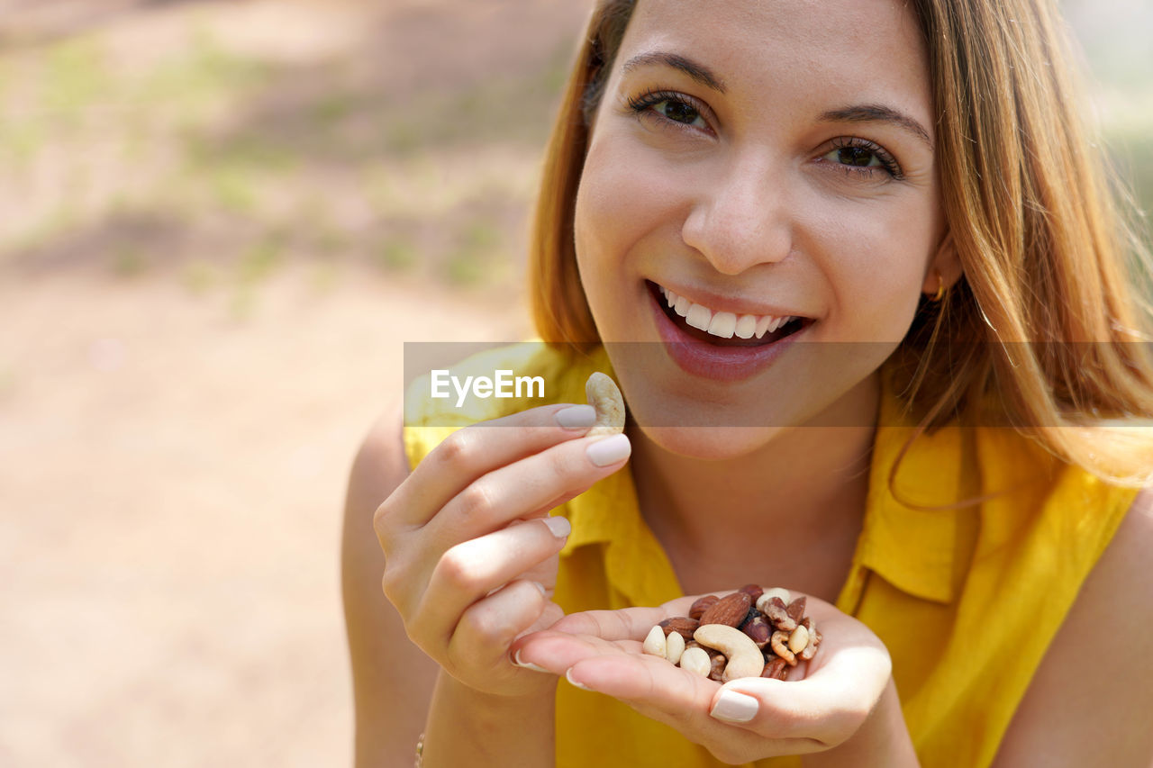Close-up of smiling girl eating a mix of nuts seed dried fruits looking at the camera