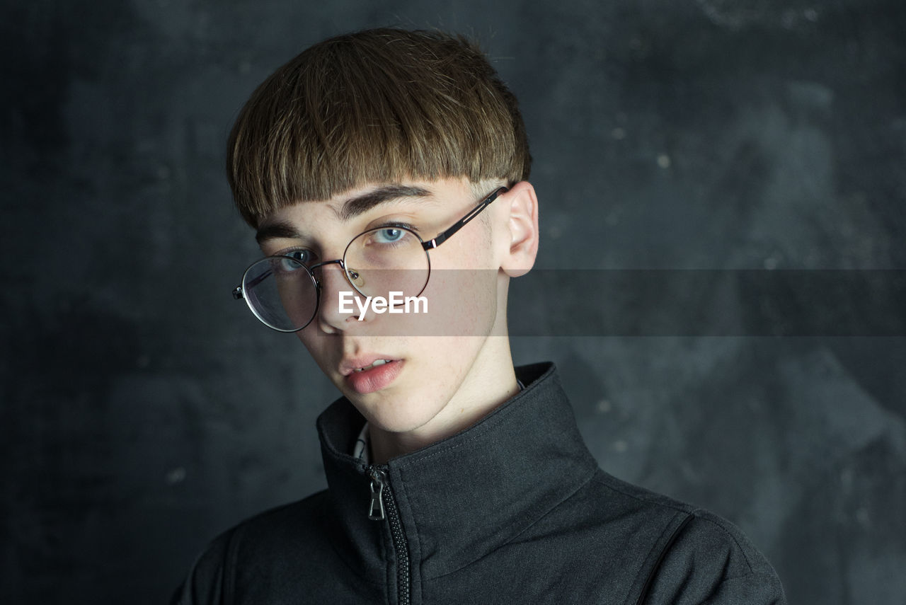 Portrait of young man against gray wall