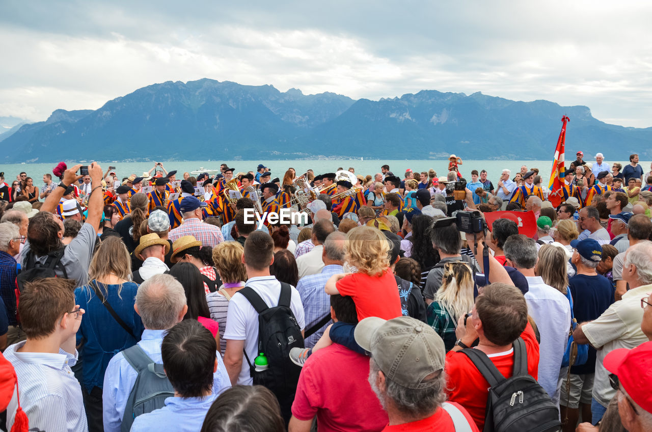 Crowd at beach during event against sky