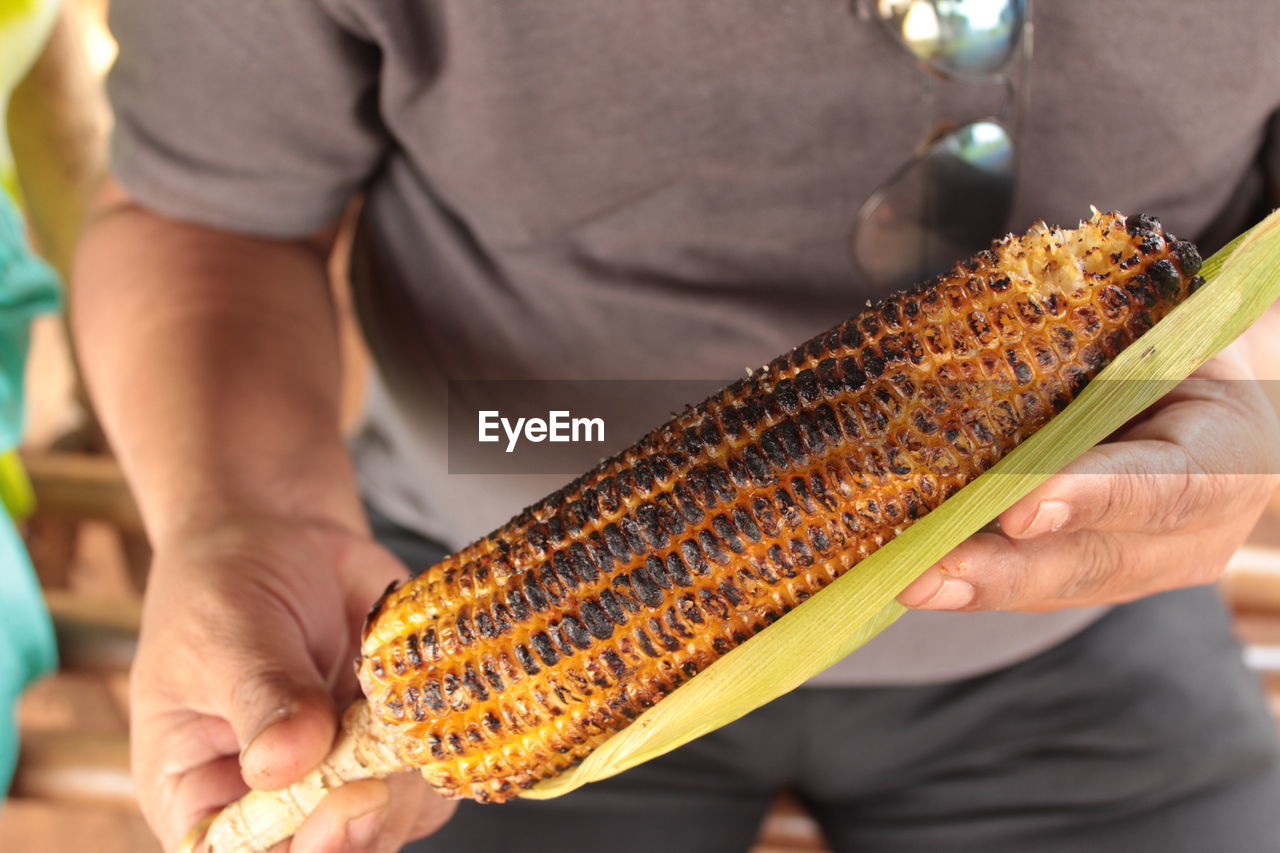 Person with grilled corn in rainy season