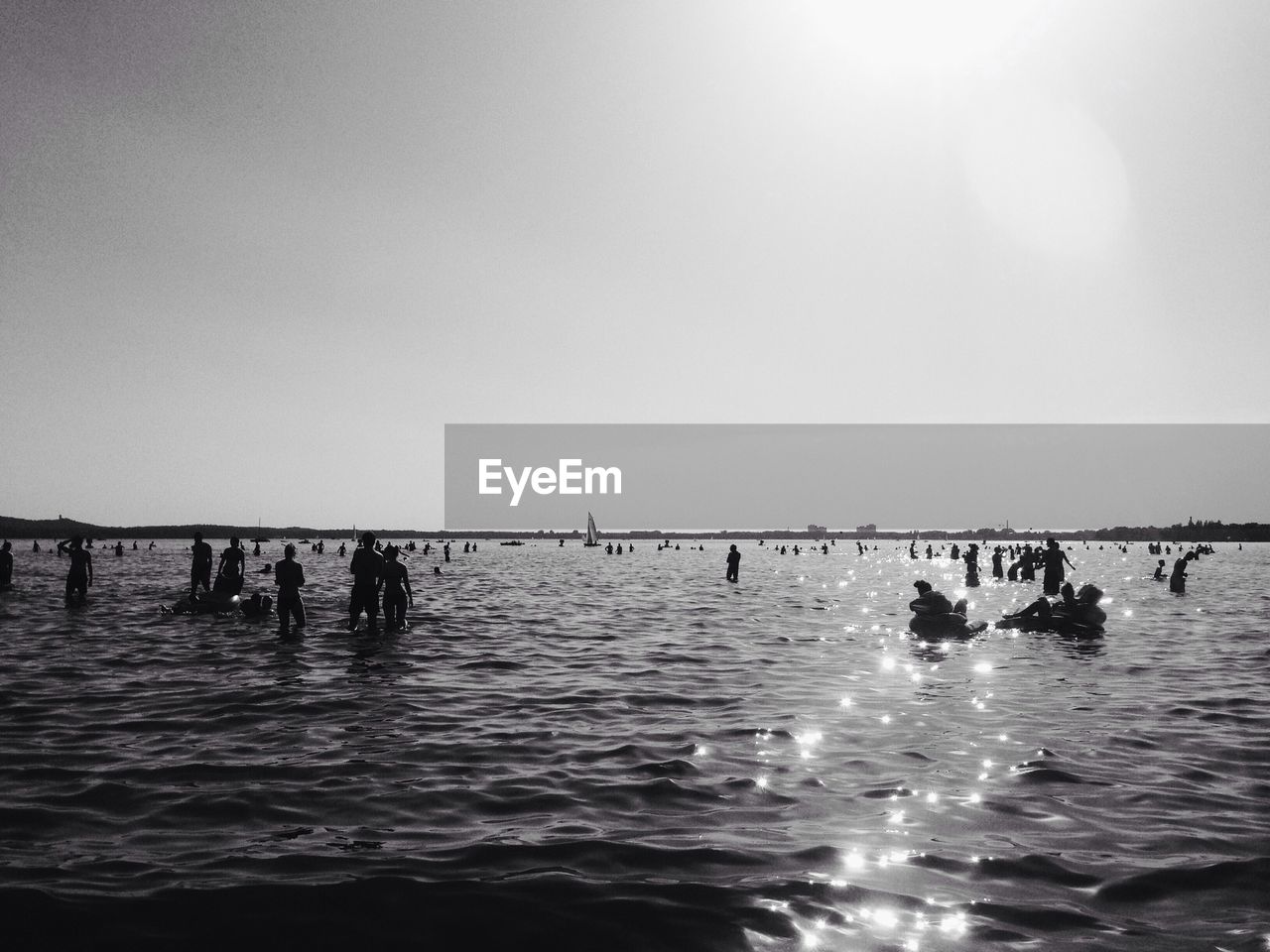 Silhouette people enjoying in sea against sky during sunny day