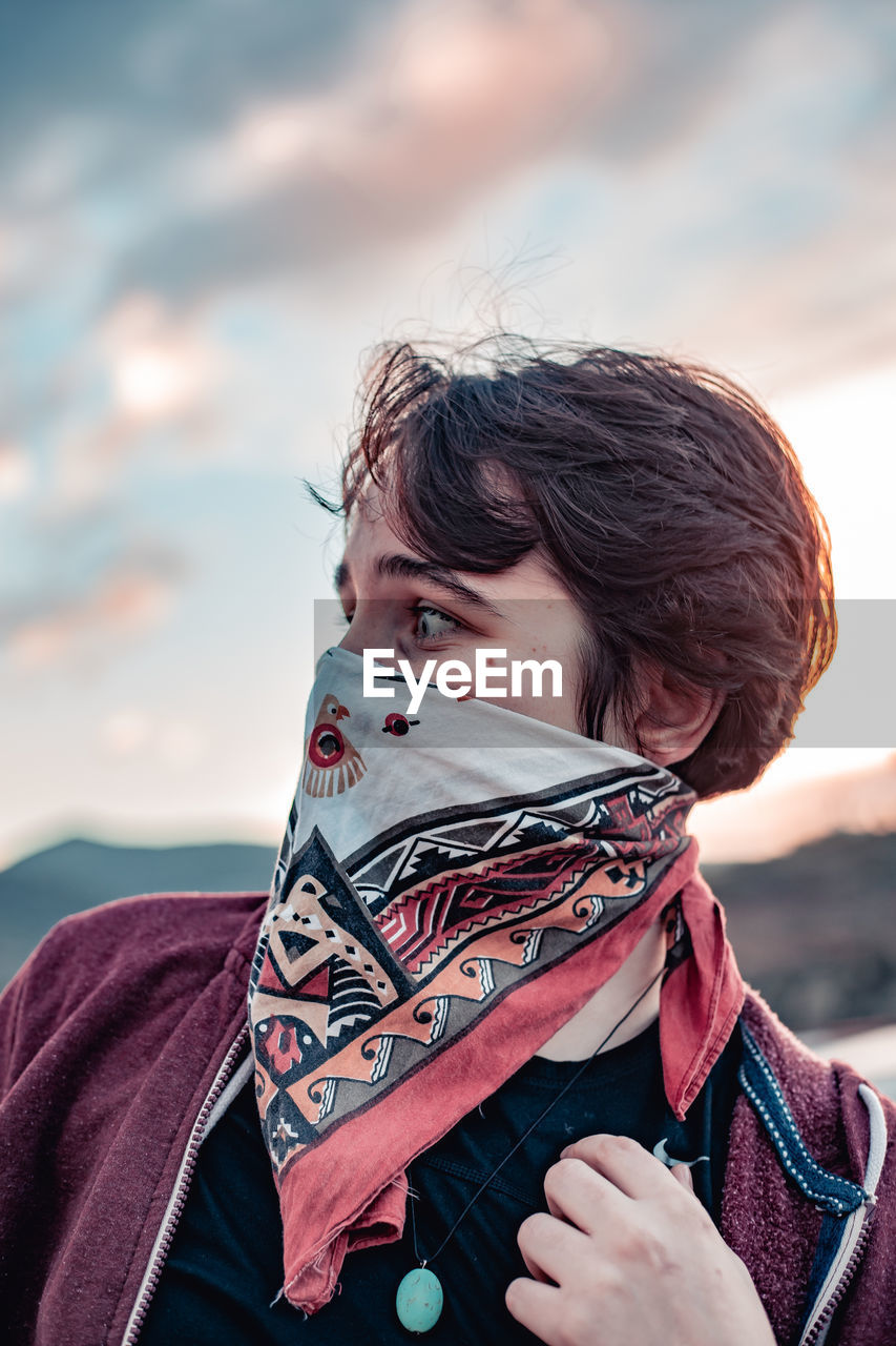 Woman wearing scarf against sky during sunset