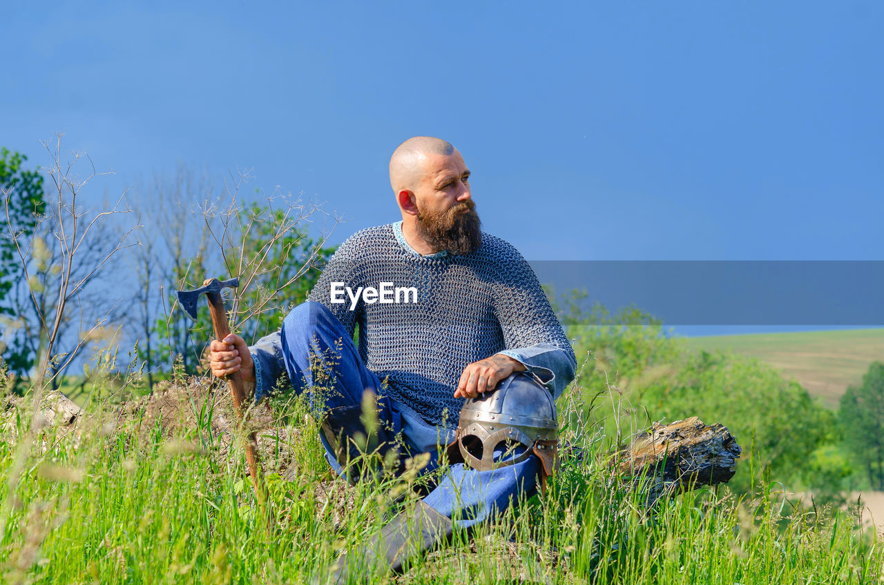 plant, adult, one person, nature, men, grass, sky, landscape, land, field, blue, rural scene, day, meadow, casual clothing, grassland, copy space, rural area, wilderness, leisure activity, clear sky, mature adult, outdoors, front view, occupation, person, sitting, looking, relaxation, mountain, environment, sunny, activity, growth, adventure, holding, lifestyles, prairie, sunlight, green, beauty in nature, agriculture, scenics - nature, senior adult, tree, three quarter length, walking, non-urban scene