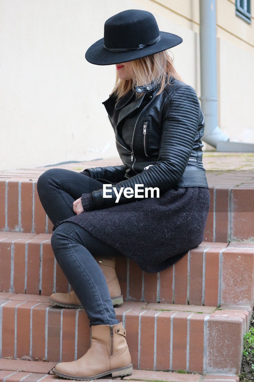 Woman wearing hat while sitting on staircase