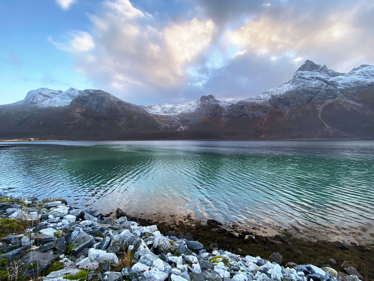 Scenic view of lake by snowcapped mountains against sky