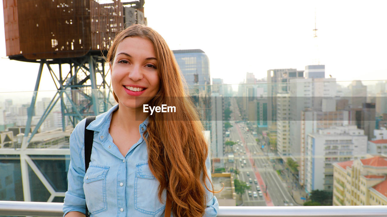 Portrait of smiling young woman standing by window