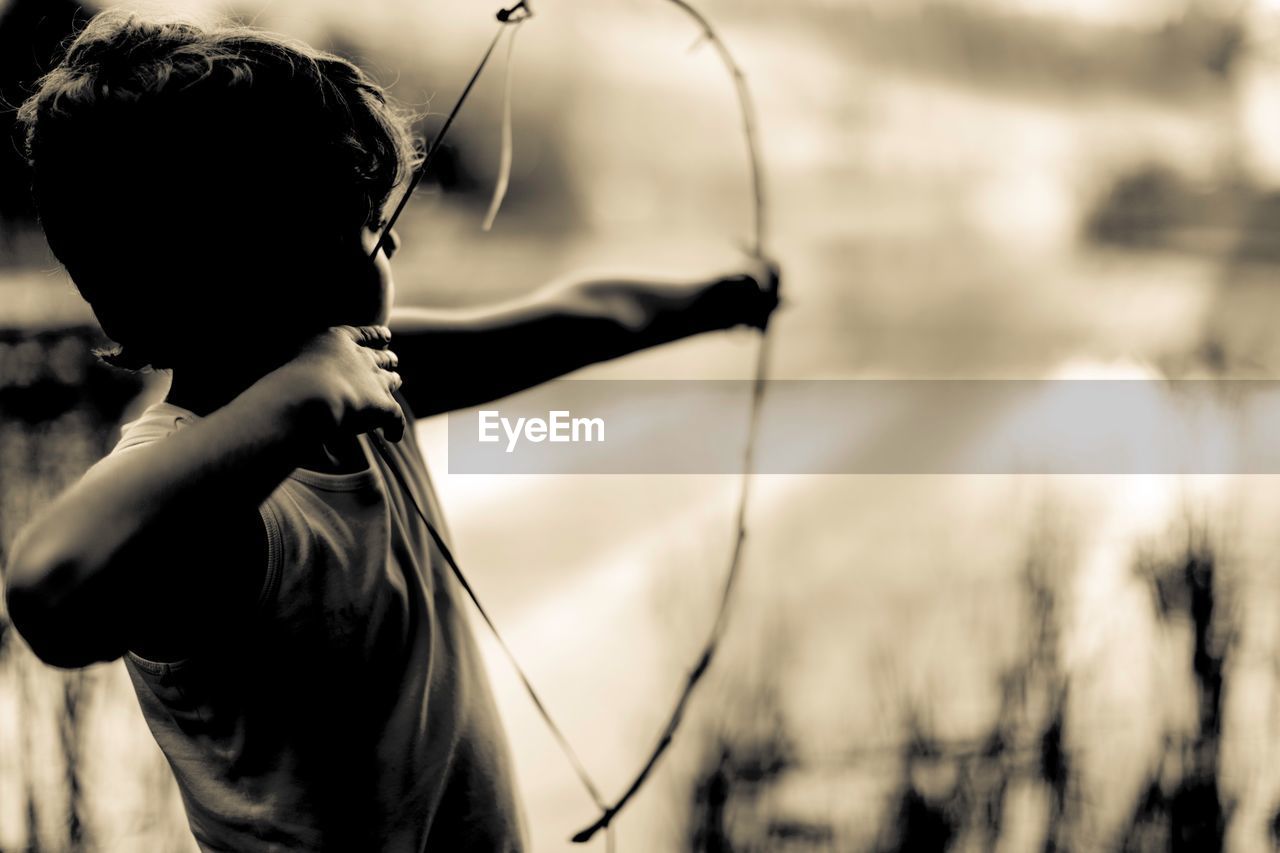 Side view of boy with bow and arrow