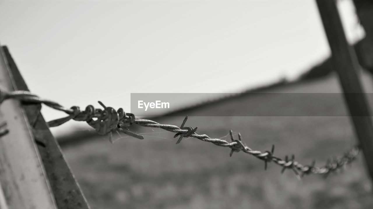 Close-up of barbed wire fence on field