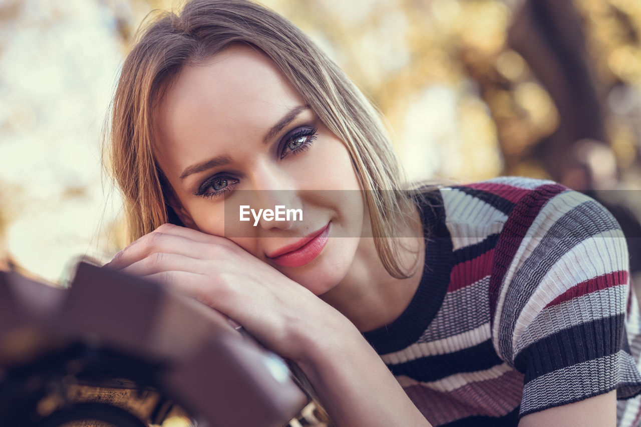 Portrait of woman sitting on bench at park