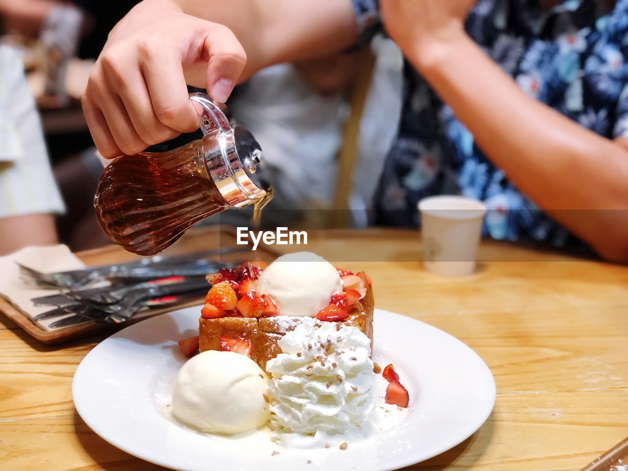 Man hand pouring honey on honey strawberry toast