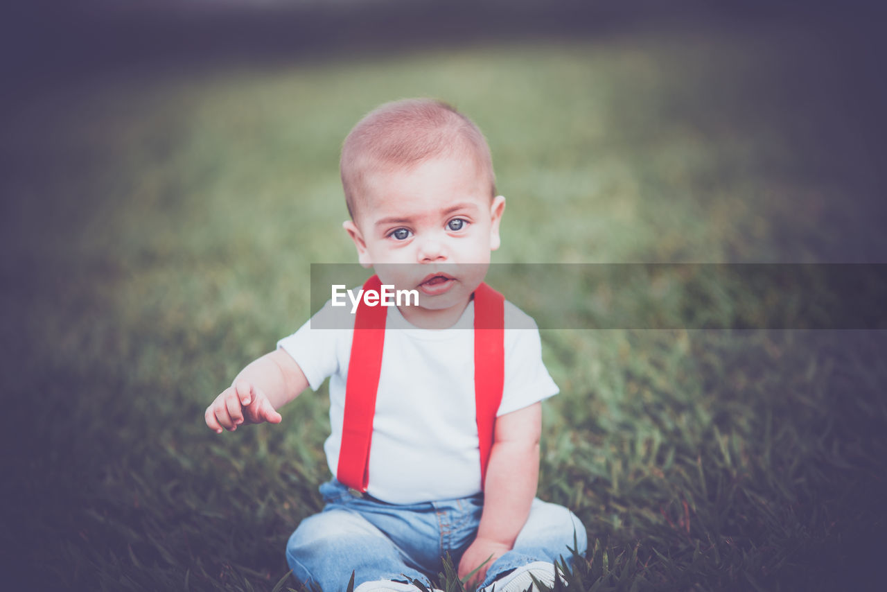 Portrait of cute boy sitting on grass