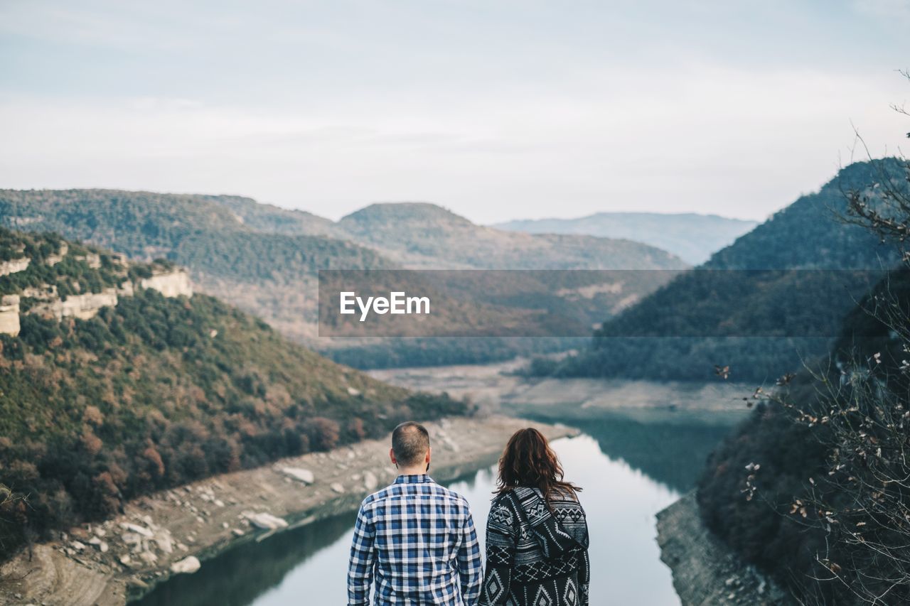 Couple looking at lake against mountains