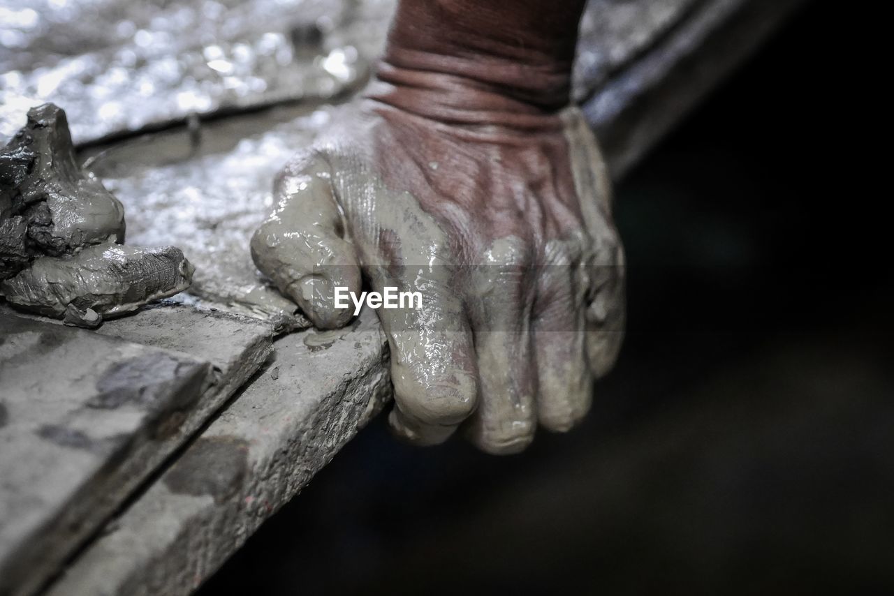 Cropped messy hands holding wood