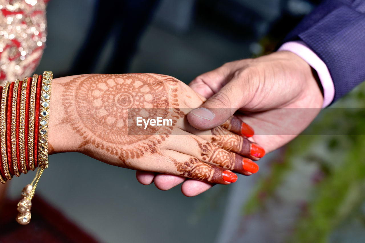 CLOSE-UP OF WOMAN HAND HOLDING HANDS WITH TATTOO