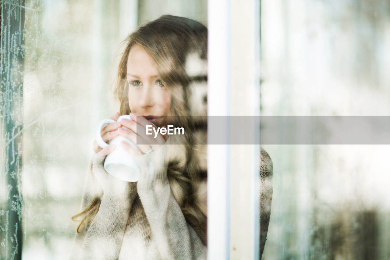 Defocused image of young woman having coffee at home