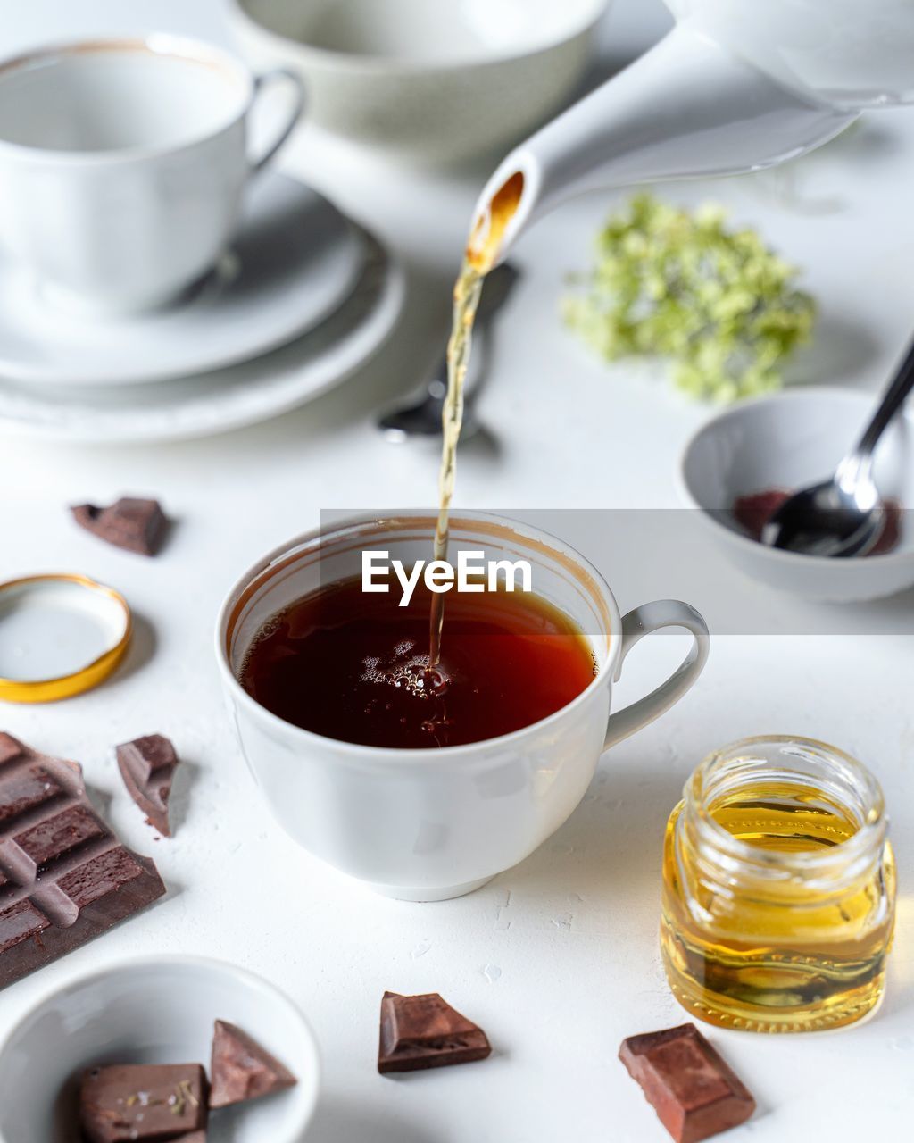 Tea in white cup, chocolates, honey on white background