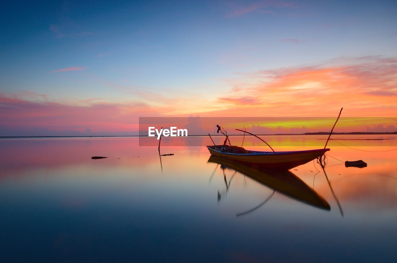 Silhouette fishing boat in sea against sky during sunset