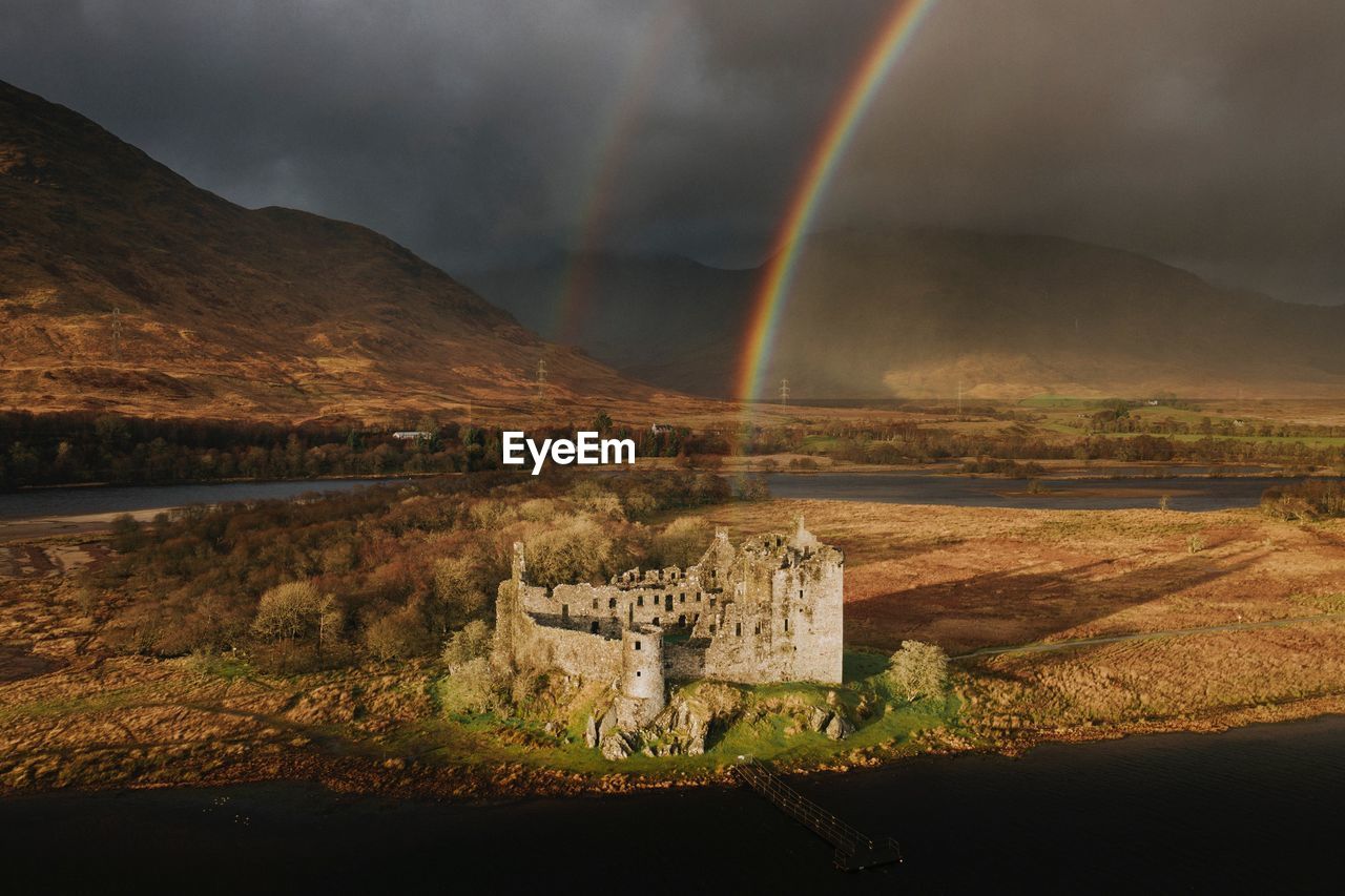 SCENIC VIEW OF RAINBOW OVER LAKE AGAINST MOUNTAIN