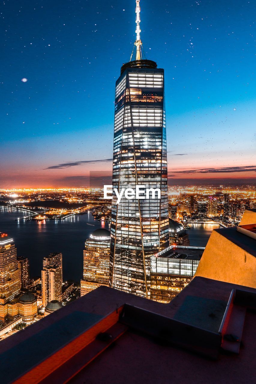 ILLUMINATED MODERN BUILDINGS AGAINST SKY AT NIGHT