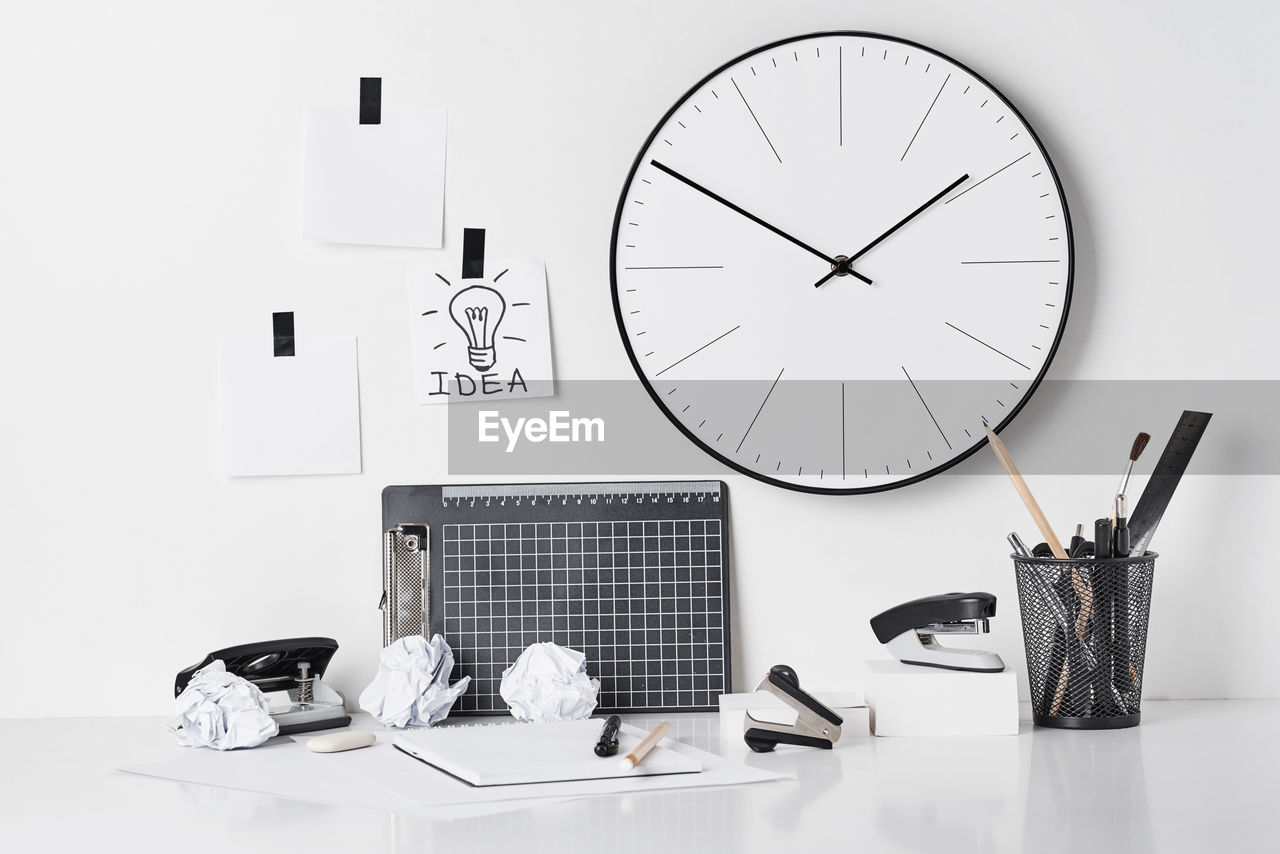 Office supplies on table with wall clock