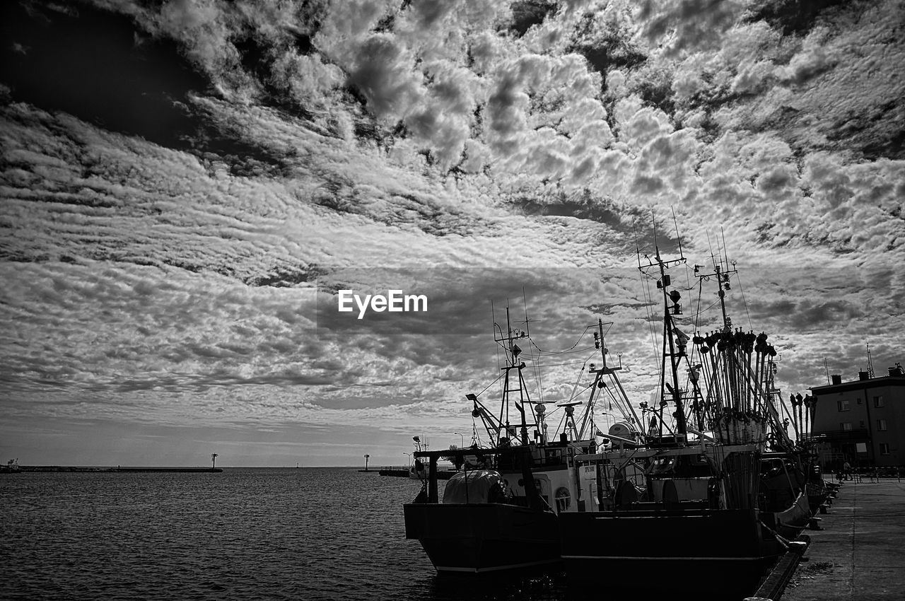 SAILBOATS MOORED AT SEA AGAINST SKY