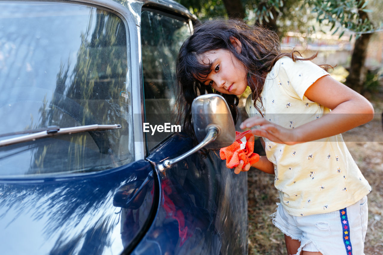 Girl watching a mirror of the car before washing it