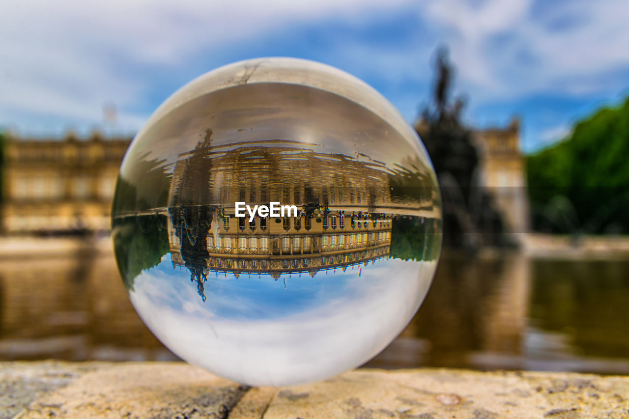 Close-up of crystal ball on water against sky