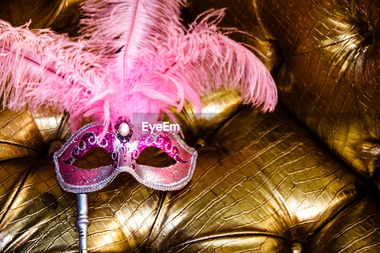 Pink venetian carnival mask on golden background.