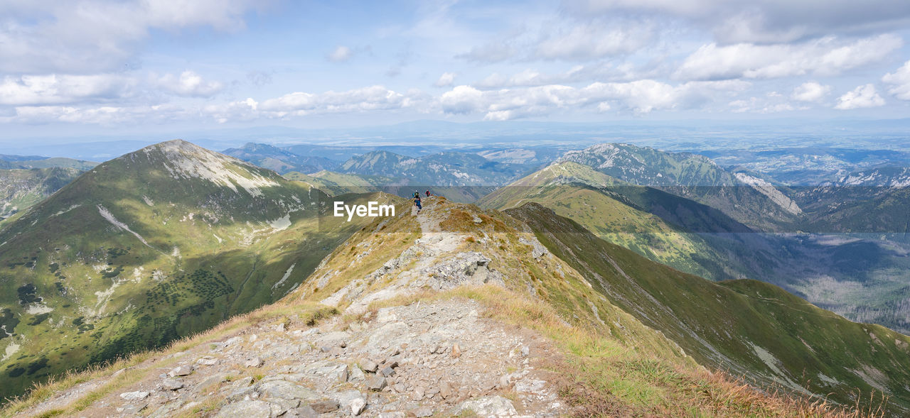 Alpine panorama with mountain ranges and hiker going through them on a sunny day, slovakia, europe