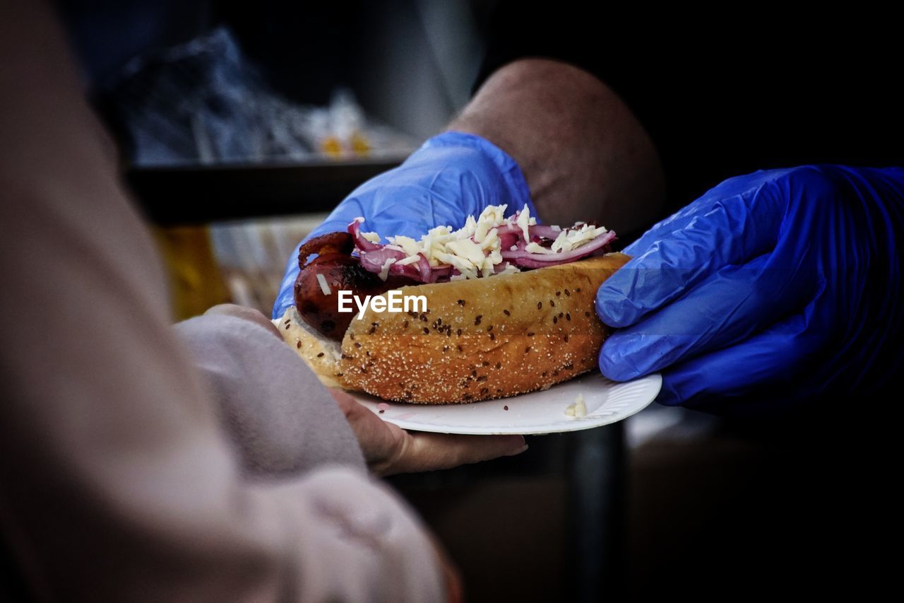 Cropped hands of male vendor giving hot dog to customer