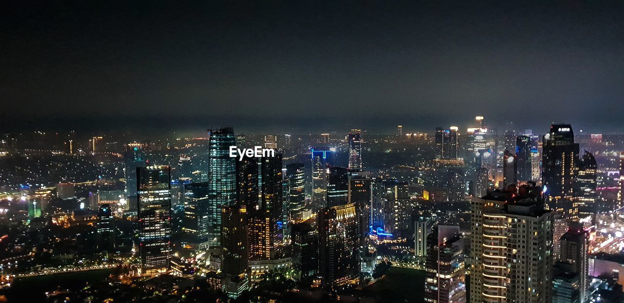 Illuminated cityscape against sky at night