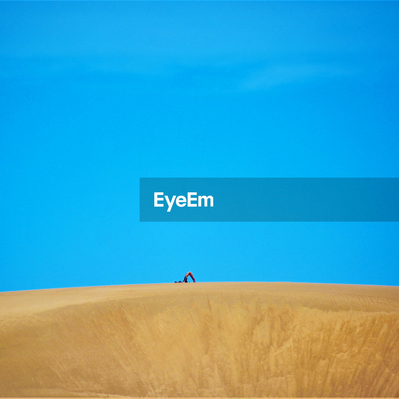 Low angle view of man walking on roof against clear blue sky