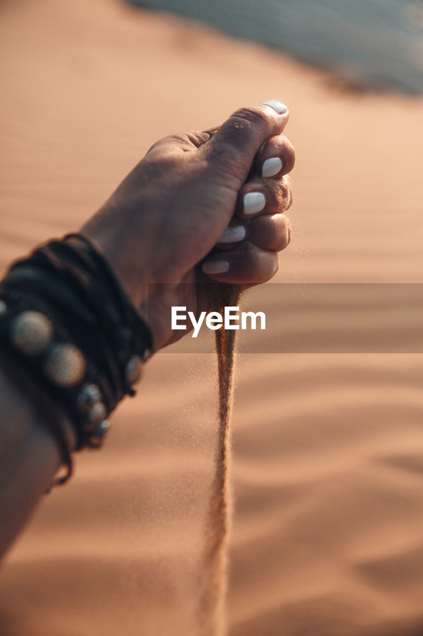 Midsection of woman holding sand on beach