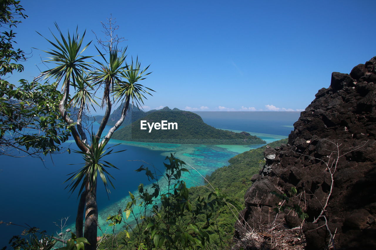 Scenic view of sea and mountains against blue sky