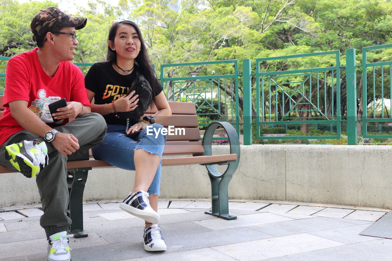 Full length of young couple sitting on seat