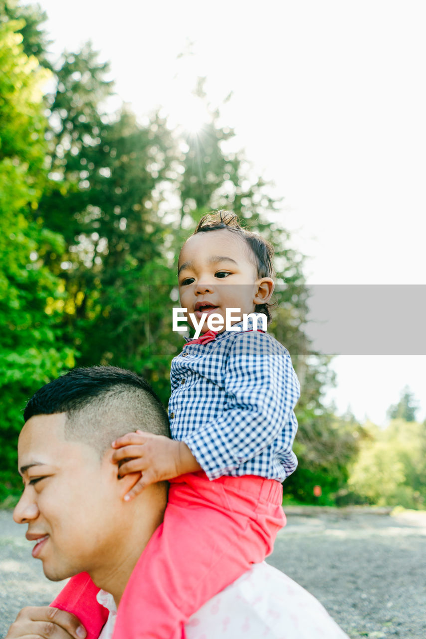 Closeup portrait of a baby boy sitting on his father's shoulders