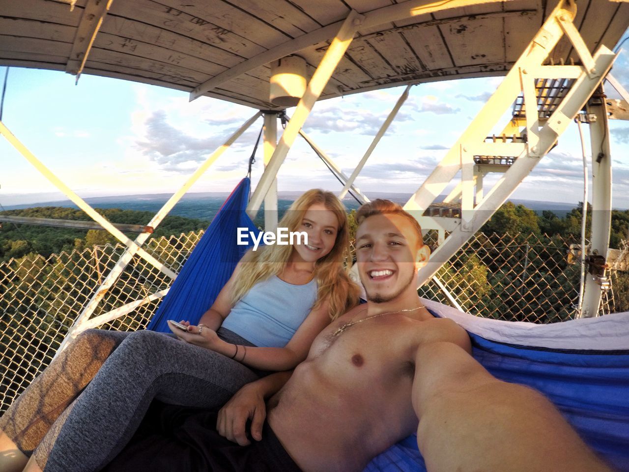 Portrait of smiling man and woman sitting in hammock